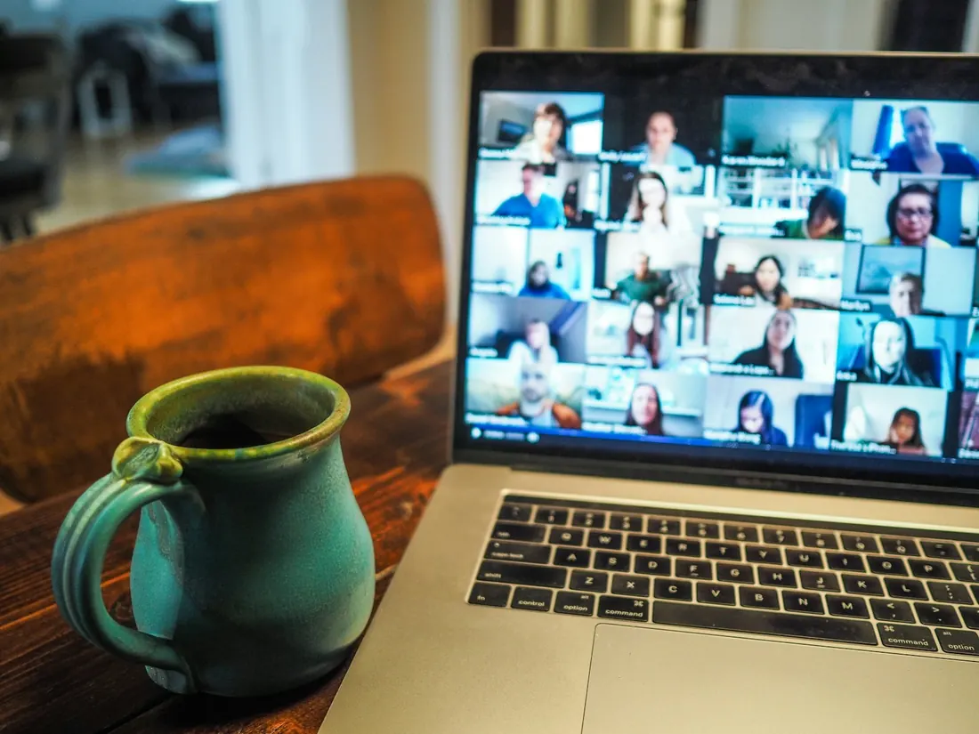 Notebook exibindo uma aula online sobre uma mesa de madeira